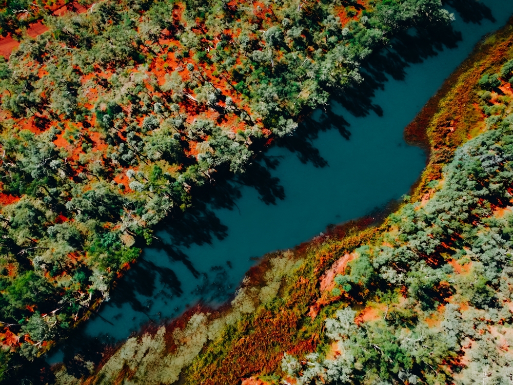 Aerial,View,Of,River,Waterhole,Surrounded,By,Red,Rocks,In